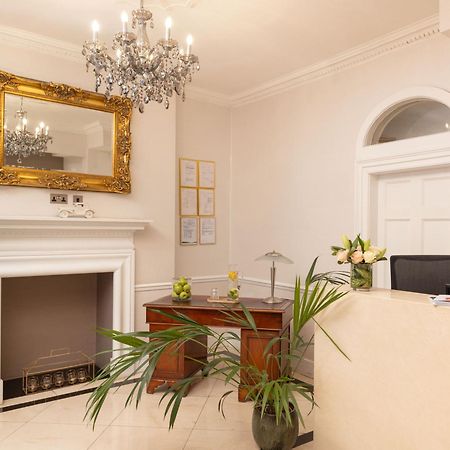 Montcalm Brewery Townhouse Hotel Londra Exterior foto The photo shows a stylish reception area. There is a decorative chandelier hanging from the ceiling, providing elegant lighting. A large, ornate mirror is mounted on the wall beside the fireplace, which features a simple, classic design. In front of 