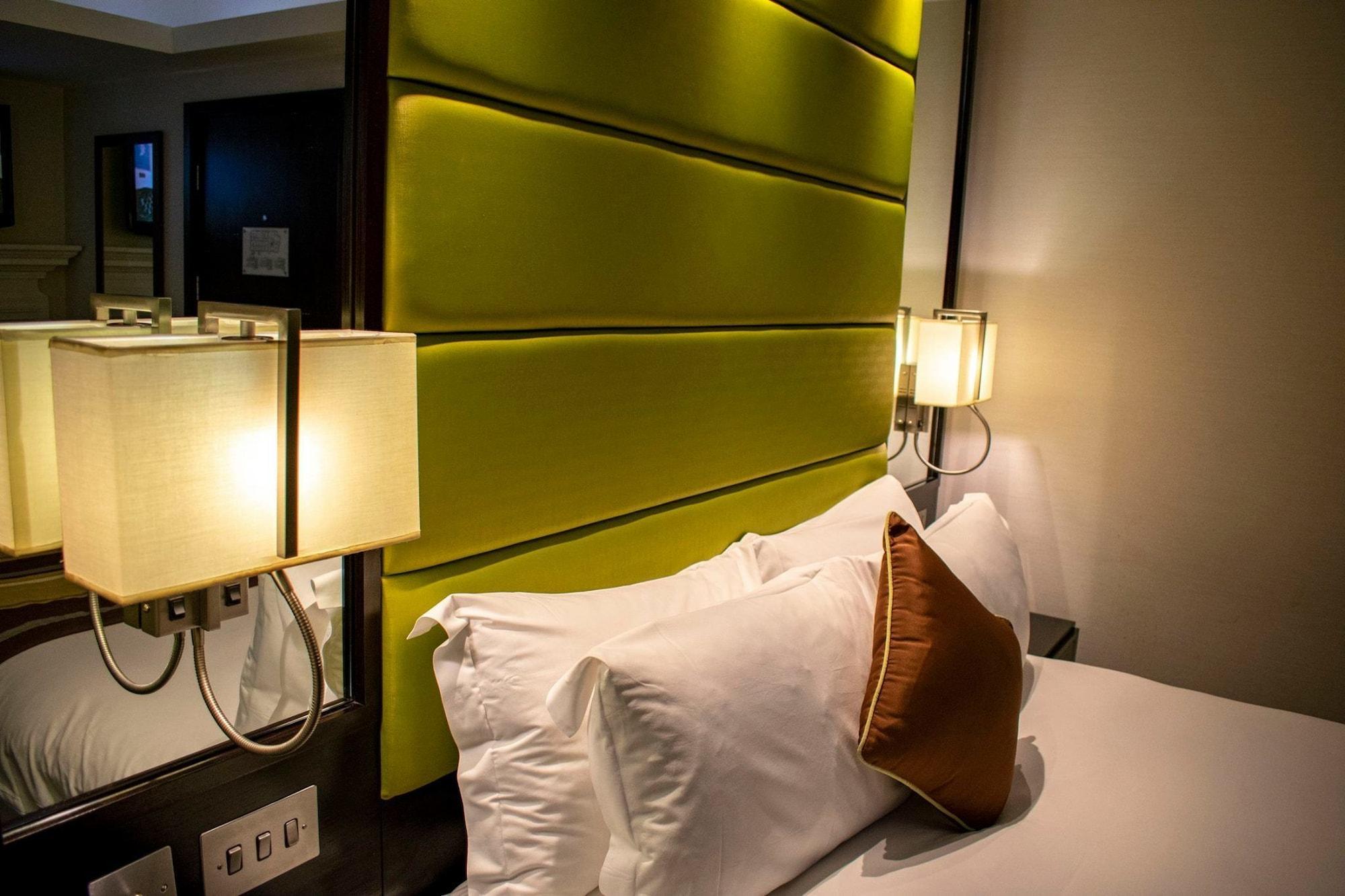 Montcalm Brewery Townhouse Hotel Londra Exterior foto The photo shows a modern hotel room with a stylish design. The focal point is a large bed with white pillows and a decorative brown pillow. The headboard is bright green and has a textured appearance. On either side of the bed, there are wall lamps t