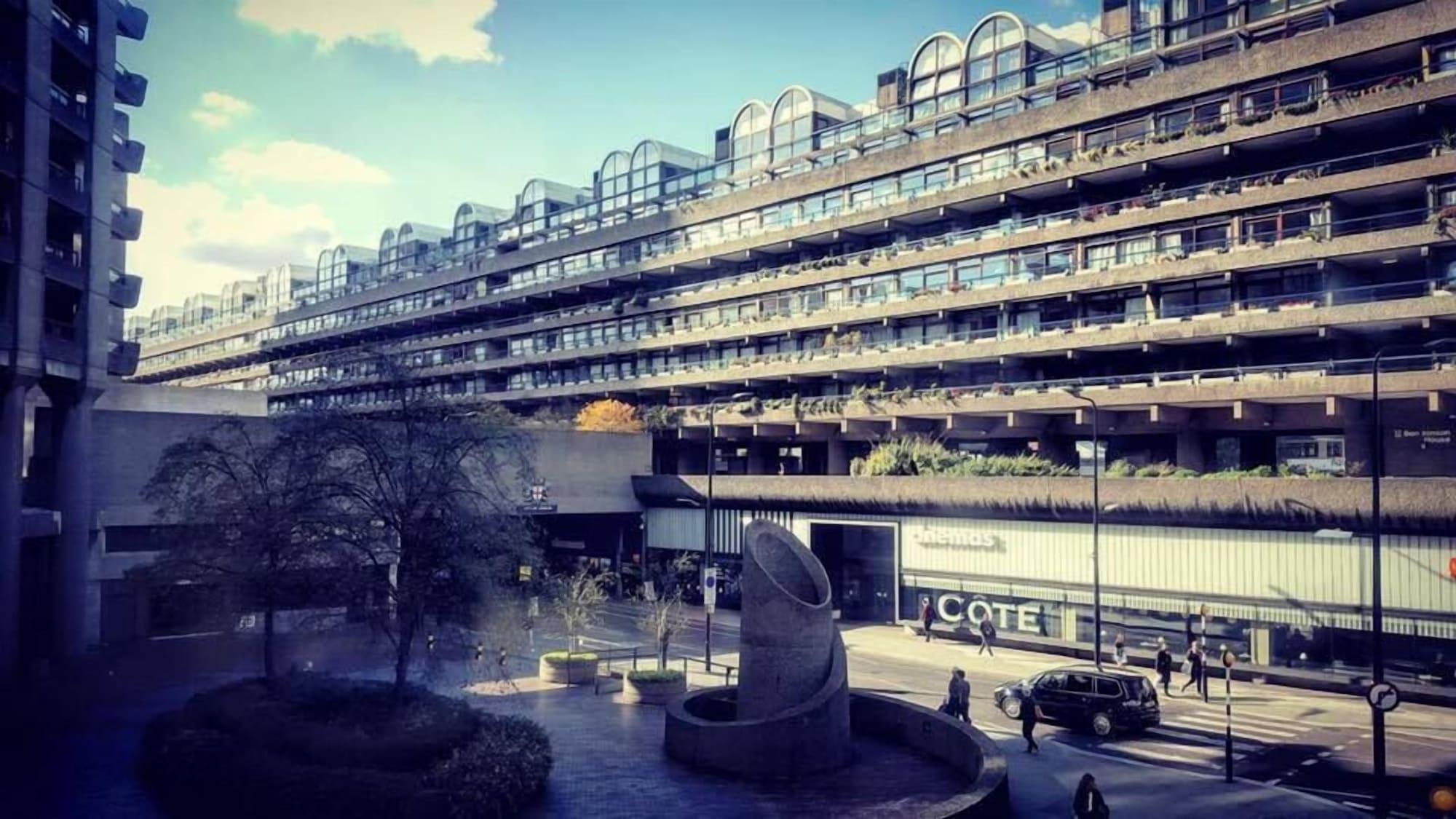 Montcalm Brewery Townhouse Hotel Londra Exterior foto The photo shows a modern architectural structure with multiple levels, featuring a series of large, rectangular balconies. Below this building, there is a plaza or courtyard area with a sculptural piece, which appears to be made of stone. Surrounding