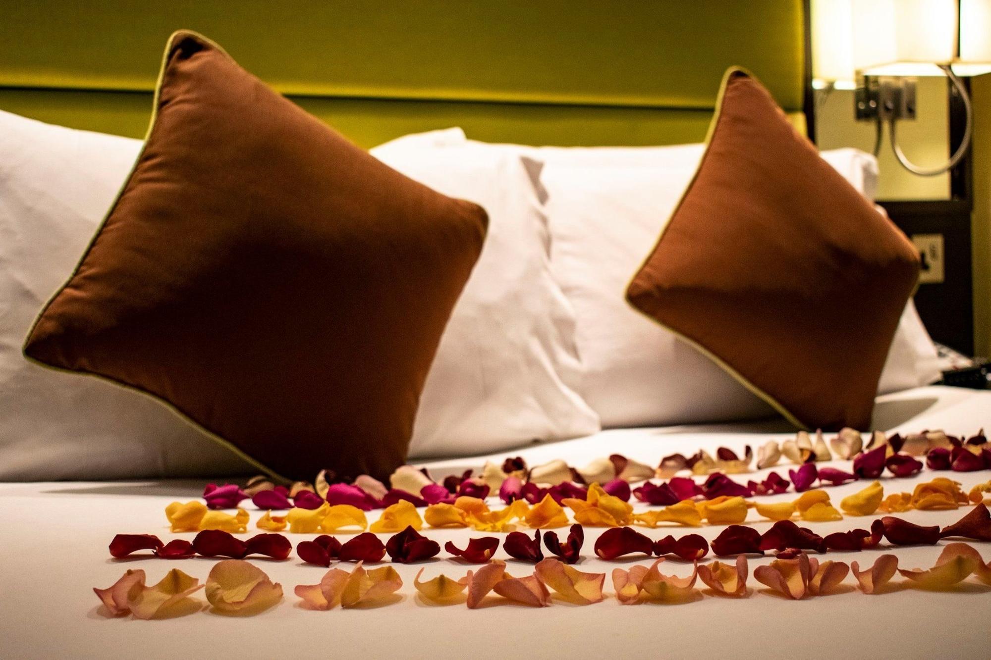 Montcalm Brewery Townhouse Hotel Londra Exterior foto The photo shows a neatly arranged bed with two white pillows and brown decorative cushions. Scattered across the bed is a decorative display of flower petals in various colors, including pink, yellow, and orange, creating a romantic or tranquil ambia