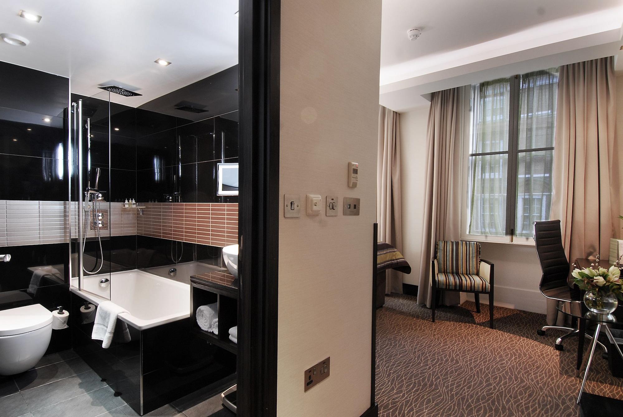 Montcalm Brewery Townhouse Hotel Londra Exterior foto The photo shows a modern hotel room that features an elegant bathroom on one side and a living area on the other. 

1. **Bathroom**: The bathroom is stylishly designed with a combination of black and white tiles. It includes a bathtub, a shower area 