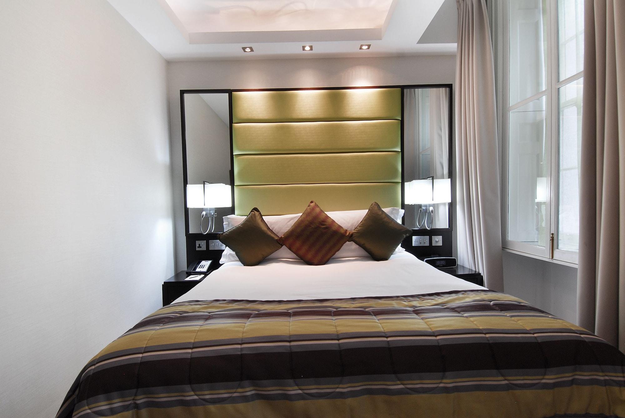 Montcalm Brewery Townhouse Hotel Londra Exterior foto The photo shows a stylishly decorated bedroom. The bed is centered in the room, featuring a white comforter with a plaid pattern in shades of brown and green. There are three decorative pillows on the bed, two in shades of brown and one in dark green