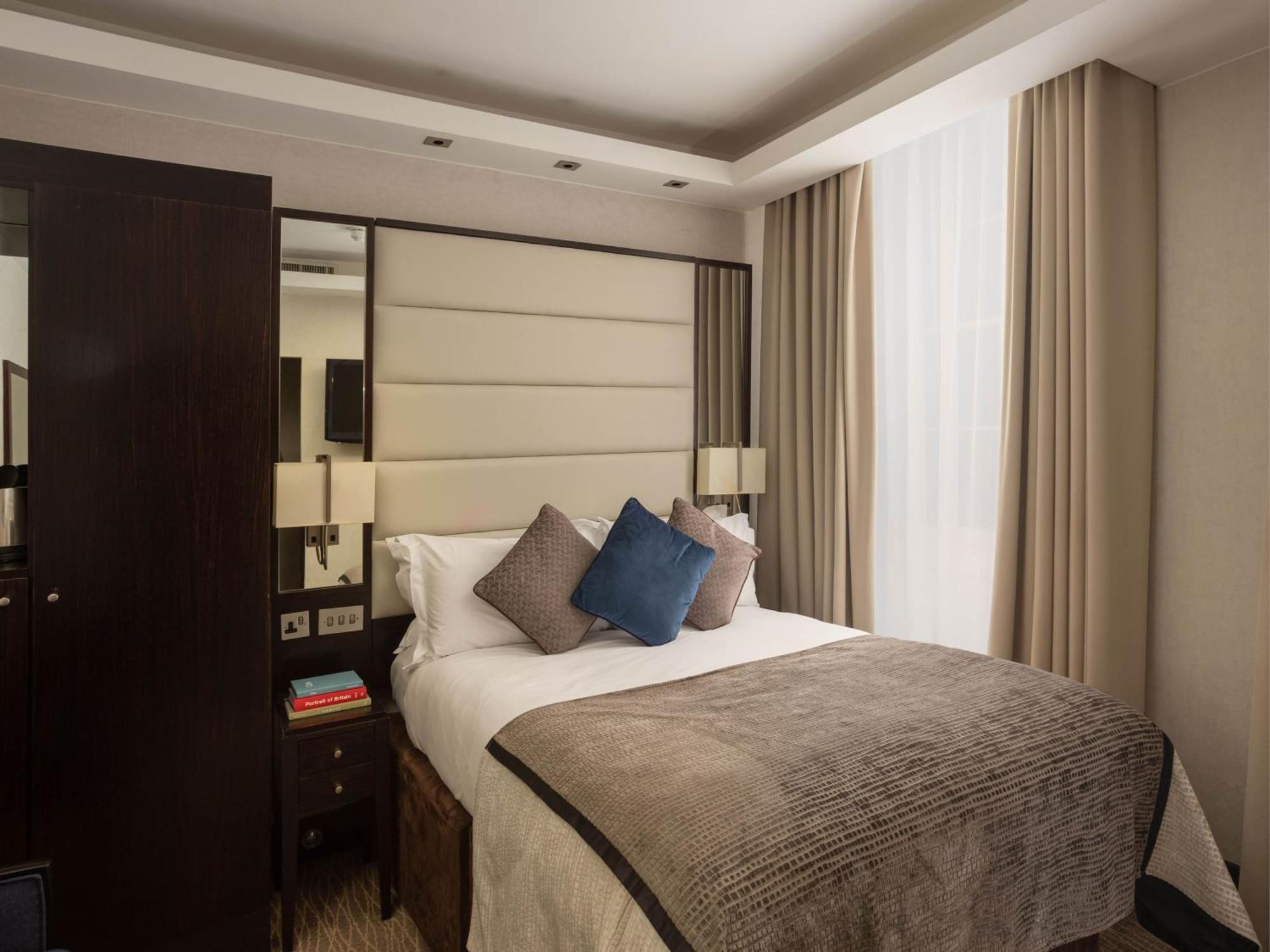 Montcalm Brewery Townhouse Hotel Londra Exterior foto The image shows a cozy bedroom. It features a comfortable double bed with a light-colored duvet and decorative pillows in shades of blue and gray. The headboard is upholstered in a soft material, and there are bedside lamps on either side of the bed.