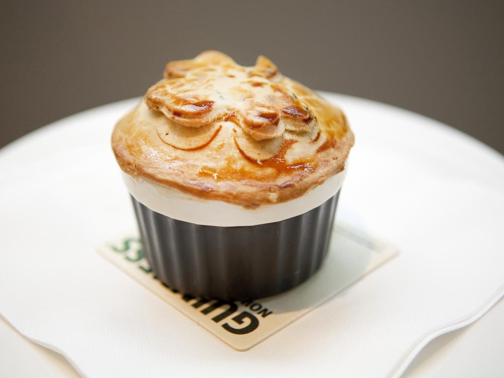 Montcalm Brewery Townhouse Hotel Londra Exterior foto The photo shows a small, individual serving of a pie, likely a savory dish. It has a golden-brown crust with decorative elements on top, resembling leaves or floral patterns. The pie is served in a black dish and placed on a white plate. The overall 