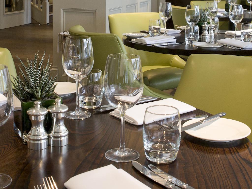 Montcalm Brewery Townhouse Hotel Londra Exterior foto The photo shows a dining setup in a restaurant. There are tables with a polished wooden surface and elegant place settings. Each setting includes multiple wine glasses and water glasses, neatly arranged with folded napkins. 

In the center, there are