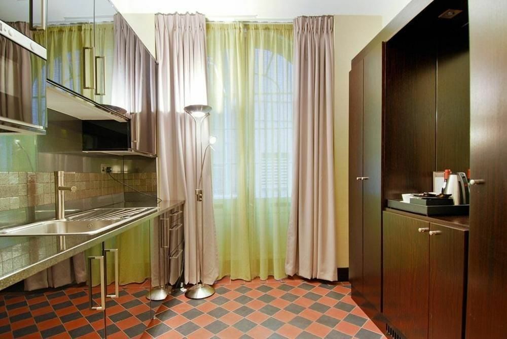 Montcalm Brewery Townhouse Hotel Londra Exterior foto The photo shows a modern kitchen area. There is metallic cabinetry and a stainless steel countertop with a sink. The walls are adorned with light-colored curtains that allow natural light to filter in, with one set in a soft purple hue and another in
