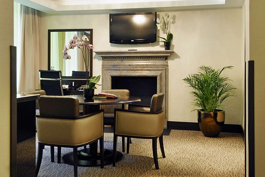 Montcalm Brewery Townhouse Hotel Londra Exterior foto The photo shows a modern and stylish room with a dining or meeting area. There is a round table surrounded by four upholstered chairs. A flat-screen television is mounted on the wall above a decorative fireplace. To the side, there is a mirror reflec