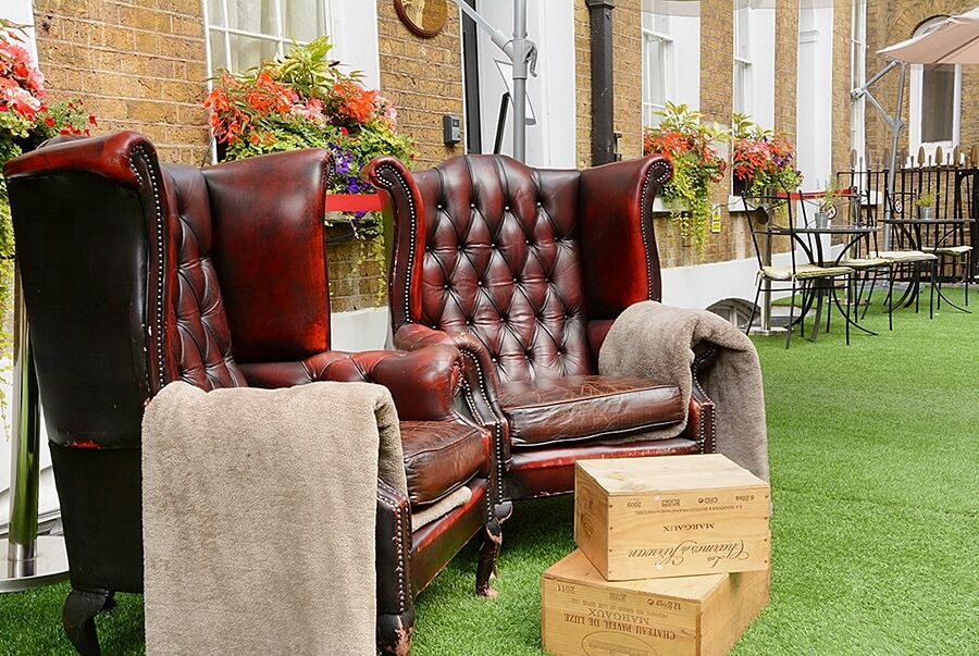 Montcalm Brewery Townhouse Hotel Londra Exterior foto The photo depicts two large, elegant armchairs with a classic design, featuring rich burgundy leather upholstery and button tufting. They are positioned in a cozy outdoor setting, with lush green artificial grass beneath them. Next to the chairs, the